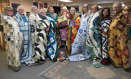 Bear's Paw Quilt staffers  wrapped in their quilts